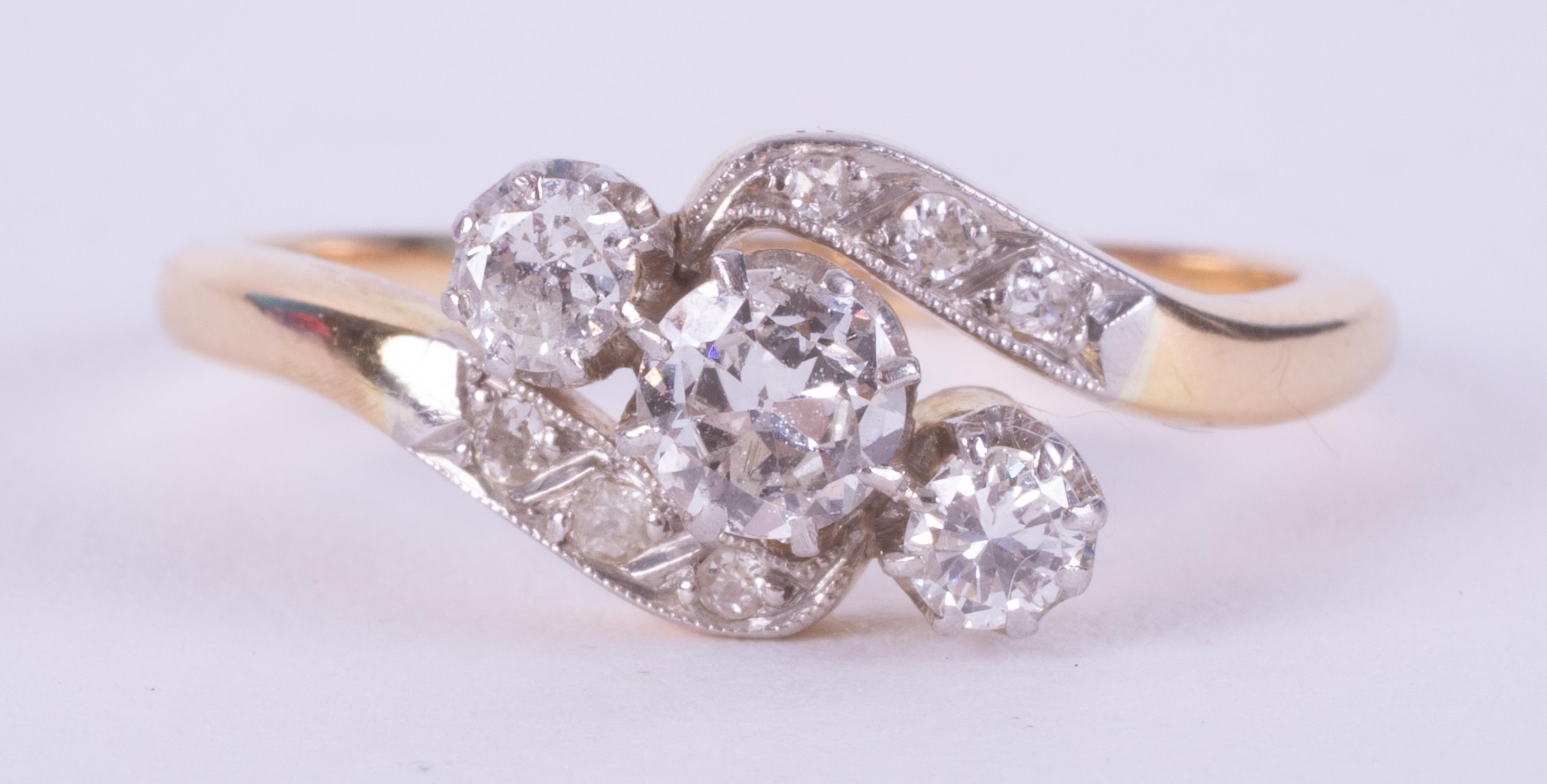 An 18ct yellow gold & platinum crossover style ring set with three round brilliant cut diamonds