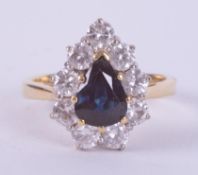 An 18ct yellow & white gold pear shaped cluster ring set with a central pear shaped sapphire