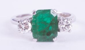 An 18ct white gold three stone ring set with a central emerald cut emerald, approx. 1.95 carats with