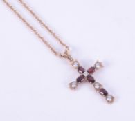 A 9ct yellow gold cross set with oval cut garnets interspaced with cubic zirconia's with a
