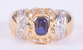 An ornately designed 18ct yellow & white gold ring set with a central emerald cut sapphire approx.