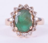 A yellow gold (not hallmarked or tested) cluster ring set with a central oval cut emerald, approx.