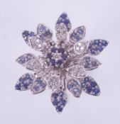 A 14ct white gold ring in a flower design set with round cut sapphires & round cut diamonds, the