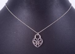 A Tiffany & Co silver pendant in the shape of a filigree heart padlock on a 16" silver chain,