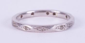 A platinum bevelled design eternity ring set with tiny round cut diamonds spaced around the band,