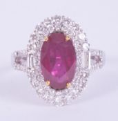An 18ct white & yellow gold ring set centrally with an oval cut ruby approx. 1.79 carats, surrounded