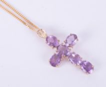 A 9ct yellow gold cross set with oval cut amethysts, length approx. 4cm, on a 20" 9ct yellow gold