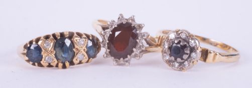 A set of three rings to include an 18ct yellow gold cluster style ring set an oval cut garnet