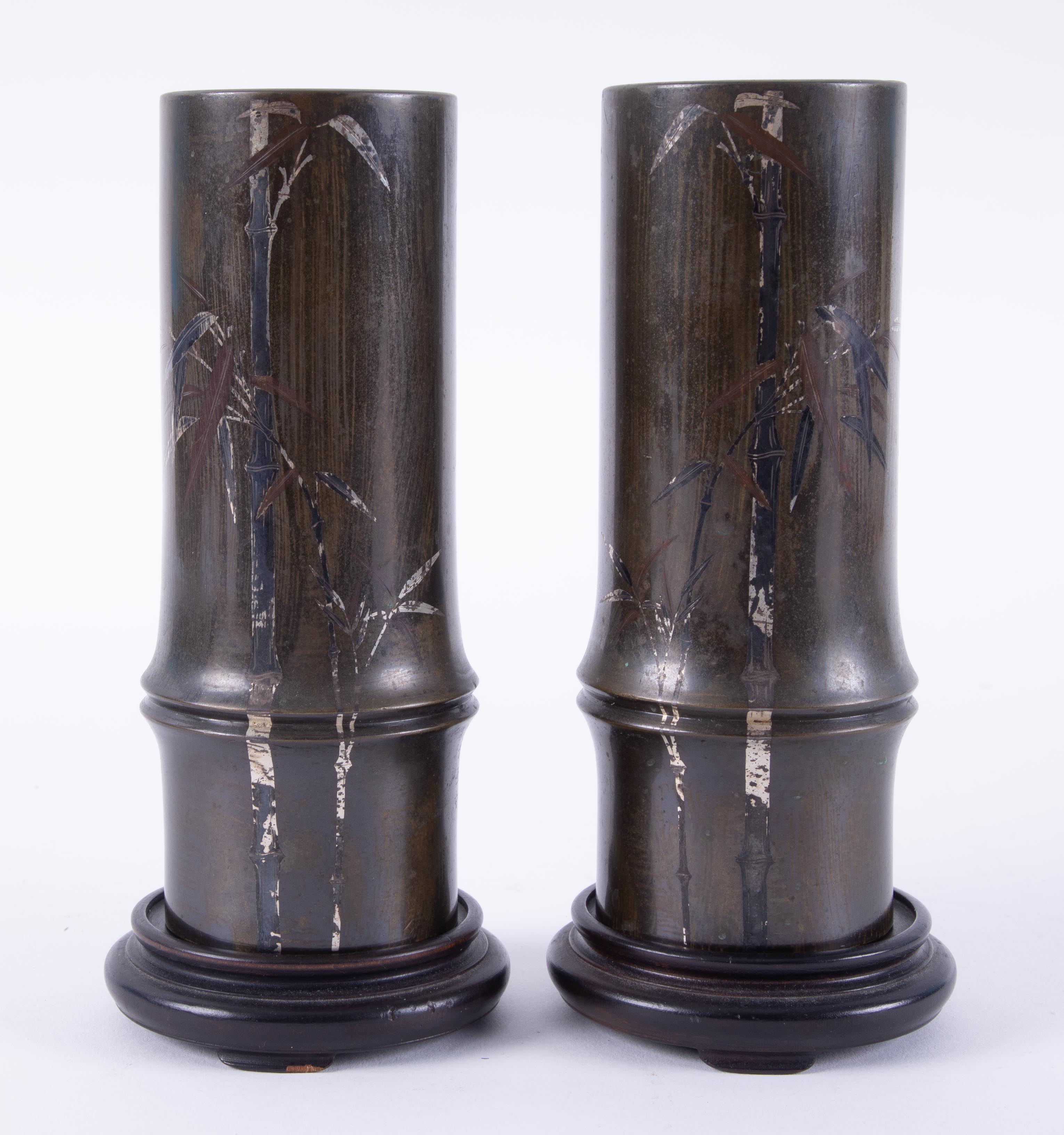 A pair of Meiji period Japanese bronze and silver overlaid vases with bamboo decoration and stands.