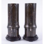 A pair of Meiji period Japanese bronze and silver overlaid vases with bamboo decoration and stands.