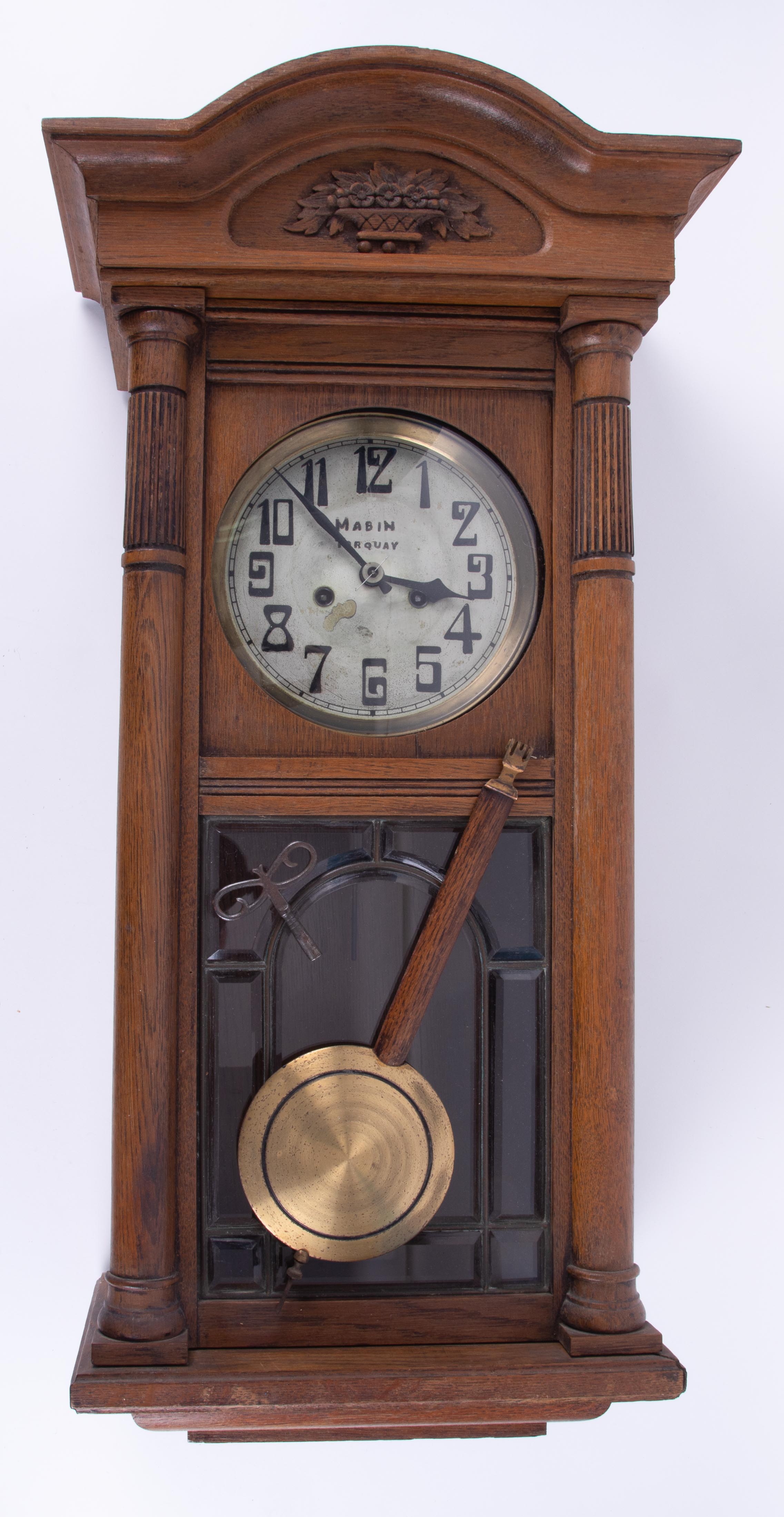 A traditional oak wall clock 'Mabin, Torquay' on dial with pendulum.