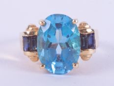 A 14ct yellow gold cocktail style ring set with a central oval cut blue stone potentially a blue