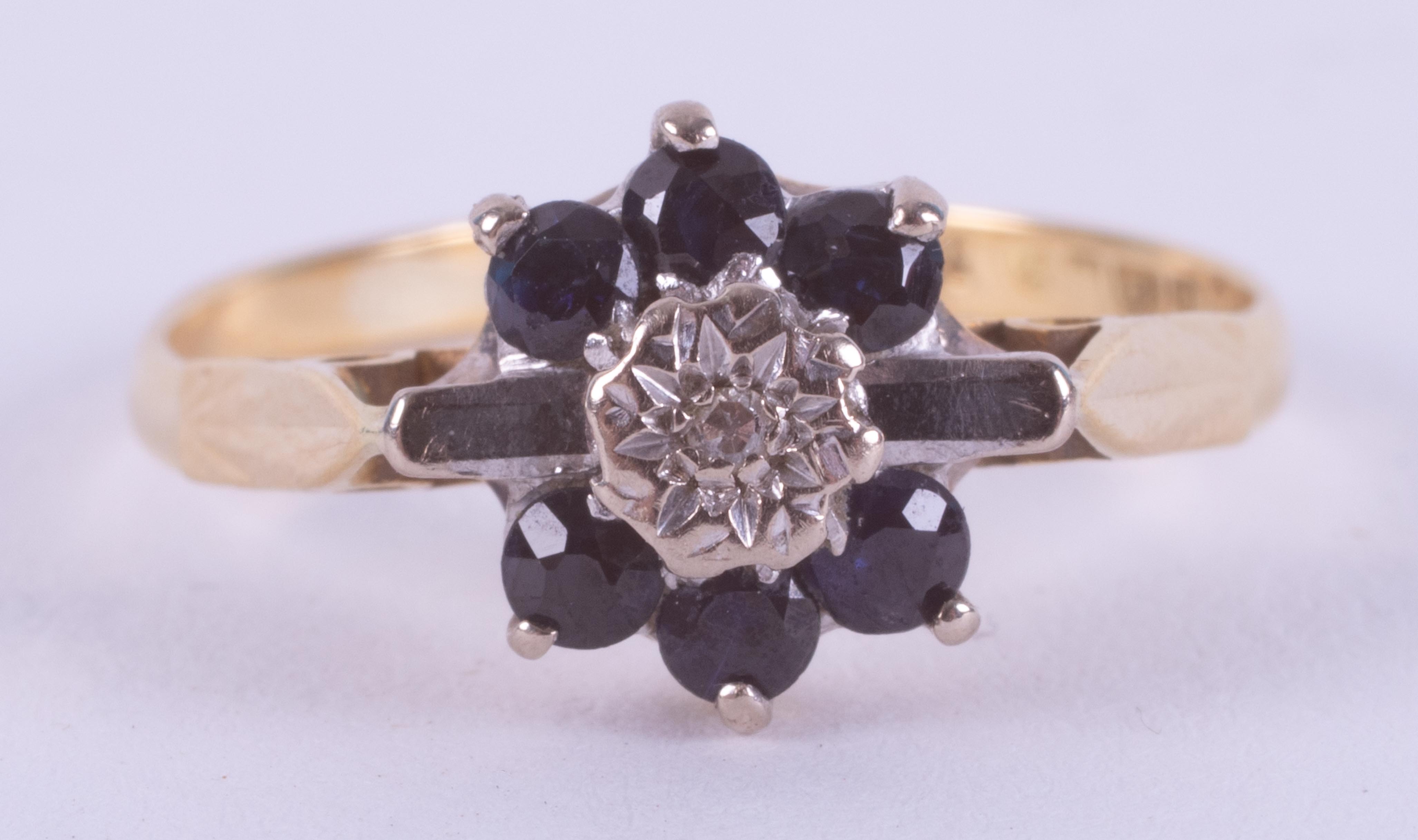 An 18ct yellow gold flower design ring set with round cut dark blue sapphires & a small