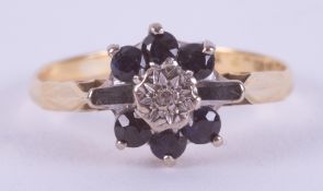 An 18ct yellow gold flower design ring set with round cut dark blue sapphires & a small