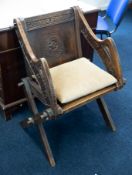 An oak Glastonbury chair with carved inscription on the back and arms.