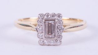 An 18ct yellow & white gold ring set with a central emerald cut diamond, approx. 0.25 carats,