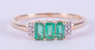 A 9ct yellow gold ring set with three baguette cut Colombian emeralds, total weight 0.55 carats with