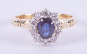 An 18ct yellow & white gold cluster ring set with a central oval cut sapphire, approx. 0.40