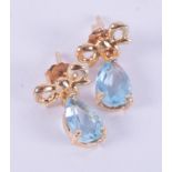 A pair of 18ct yellow gold drop earrings set with a pear shaped blue topaz and a gold bow design