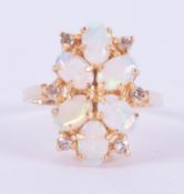 An 18ct yellow gold cluster style ring set with six oval cabochon cut white opals, sizes vary