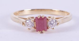An 18ct yellow gold three stone ring set with a central emerald cut ruby, approx. 0.20 carats,