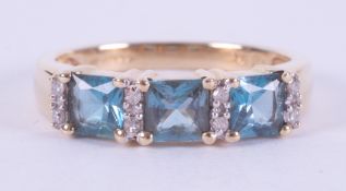 A yellow gold ring set with three square cut blue topaz, total weight approx. 1.17 carats,