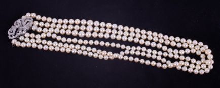 A three row cultured pearl necklace set to an ornate bow design white gold diamond set clasp, the