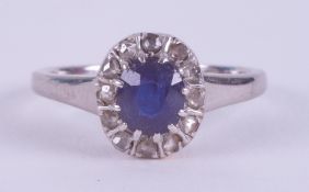 A platinum cluster ring set with a central oval sapphire, approx. 0.61 carats, surrounded by older