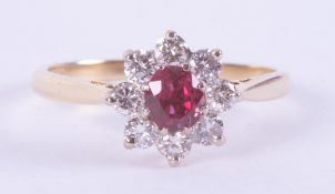 An 18ct yellow gold ring in a flower design set with a central round cut ruby, measuring approx. 0.