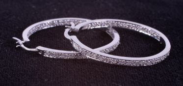 A pair of 18ct white gold hoop earrings set with round brilliant cut diamonds to the front half