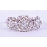 An ornate white gold (not hallmarked or tested) flower trilogy design ring set with round