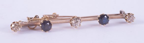 A yellow gold (not hallmarked or tested) bar brooch set with three round cut diamonds, total