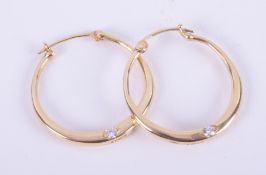 A pair of 18ct yellow gold hoop earrings set each with a single round brilliant cut diamond, total