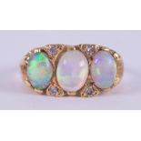 An 18ct yellow gold ring set with three oval cabochon cut white opals with good colour play, the