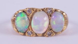 An 18ct yellow gold ring set with three oval cabochon cut white opals with good colour play, the