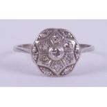 A platinum ring set with thirteen small old round cut diamonds in an illusion style flower