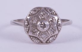 A platinum ring set with thirteen small old round cut diamonds in an illusion style flower