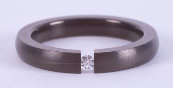 A titanium band with a tension set 0.03 carat round brilliant cut diamond, 3mm x 2.6mm, 1.77gm, size