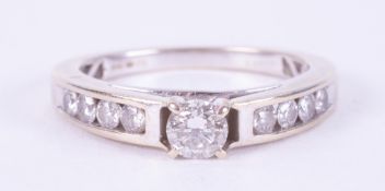 An 18ct white gold ring set with a central round brilliant cut diamond, with four round brilliant