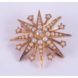 A 15ct yellow gold star brooch set with a central old round cut diamond and surrounded by seed