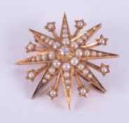 A 15ct yellow gold star brooch set with a central old round cut diamond and surrounded by seed