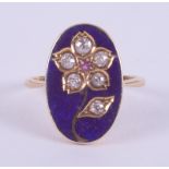 An 18ct yellow gold ring set with a central oval panel with a blue enamel background and a flower