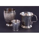 An Eastern white metal small beaker with coin base together with a foreign silver beaker with ornate