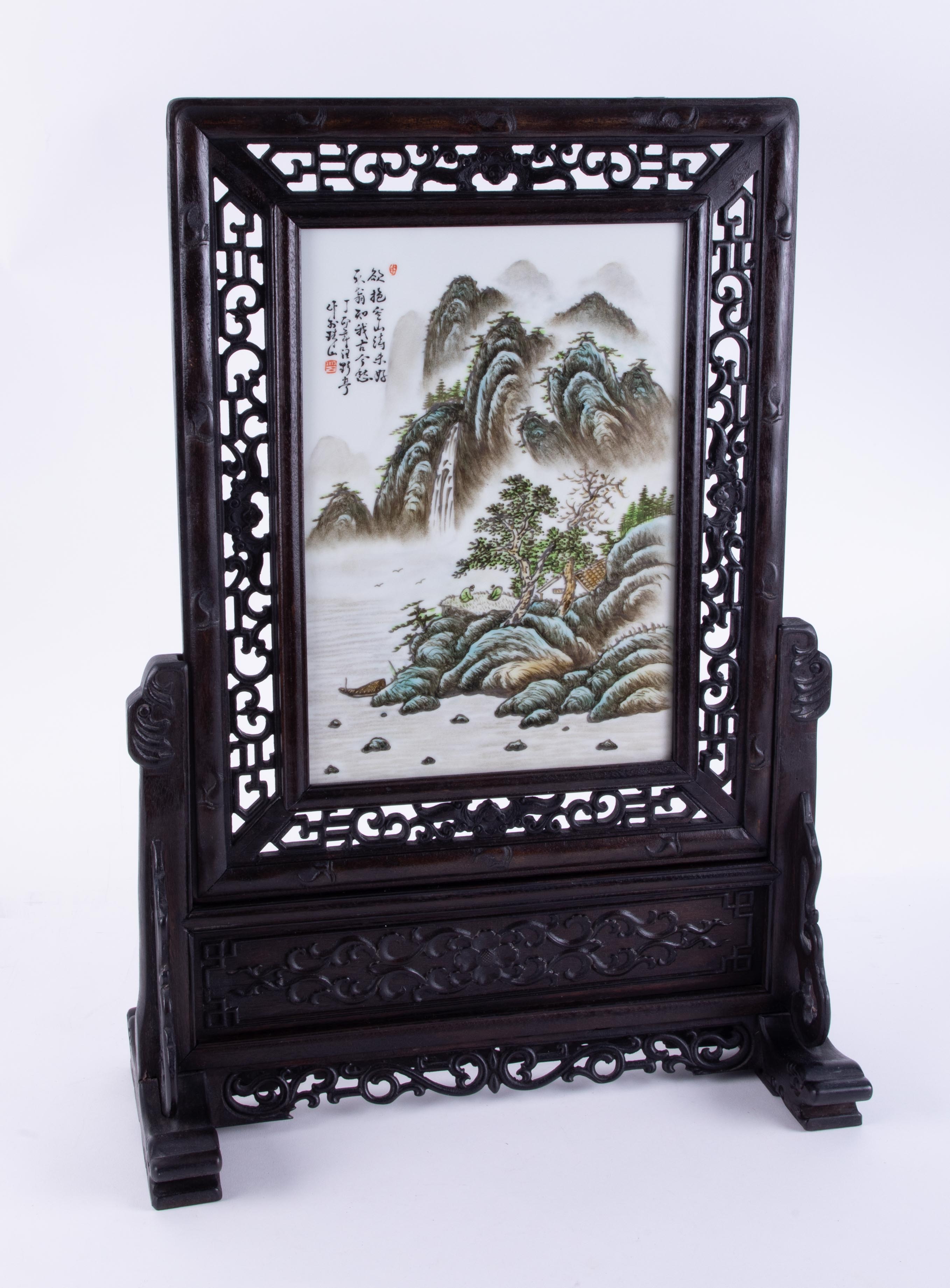 A Chinese table screen with carved wood frame set with a porcelain plaque with landscape scene,