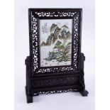 A Chinese table screen with carved wood frame set with a porcelain plaque with landscape scene,