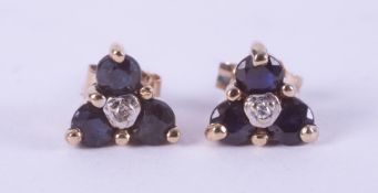 A pair of 9ct yellow gold earrings each set with three round dark blue sapphires, total sapphire