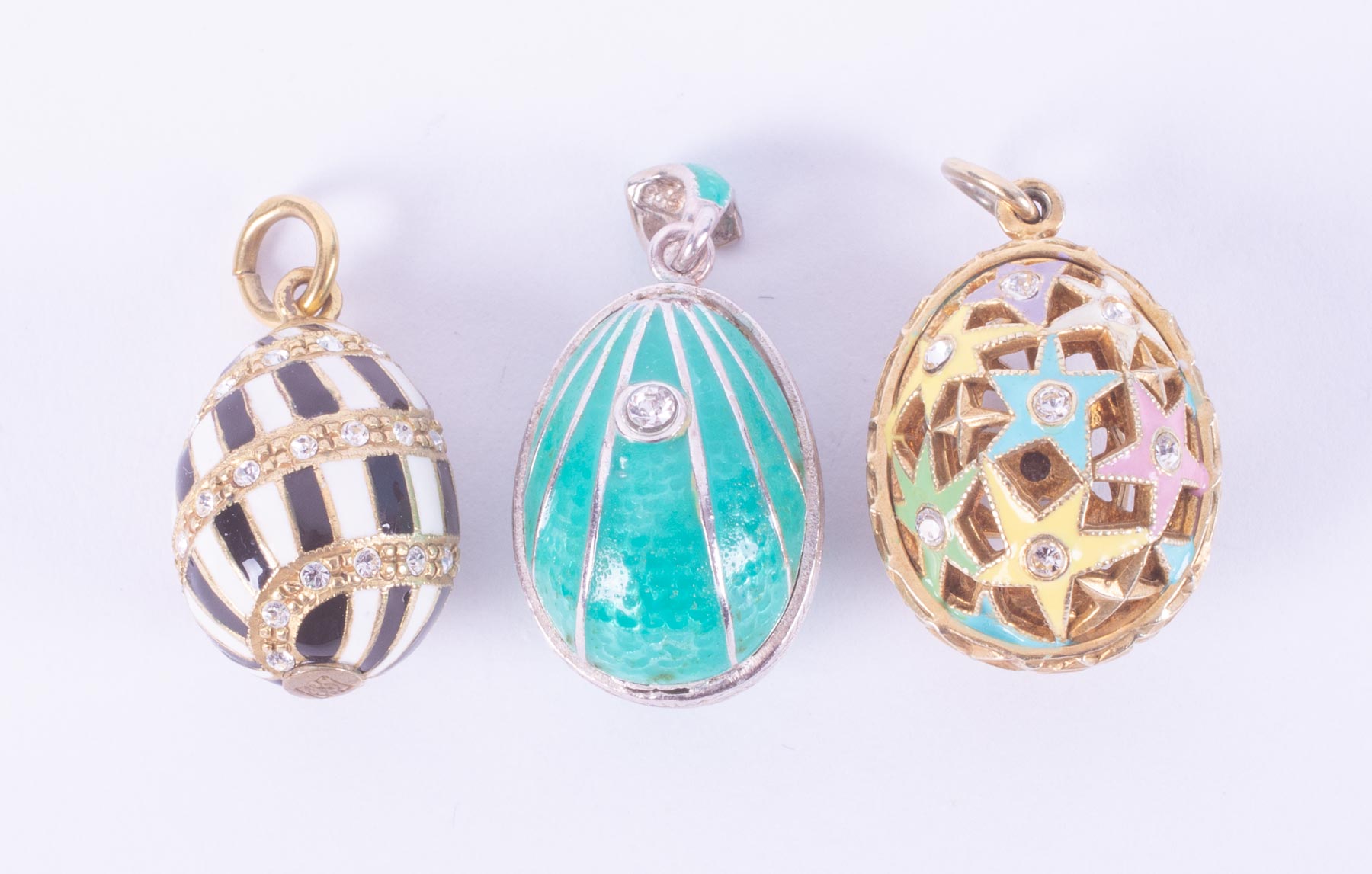 Three silver & silver gilt 'Faberge style' enamel egg pendants set with crystals, the star patterned