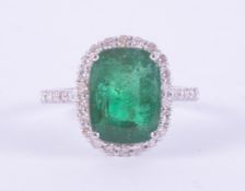 An 18ct white gold cluster design ring set with an emerald cut emerald, approx. 6.00 carats,