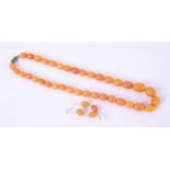 A string of oval amber beads of varying sizes with a screw clasp, four spare amber beads, length