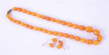 A string of oval amber beads of varying sizes with a screw clasp, four spare amber beads, length